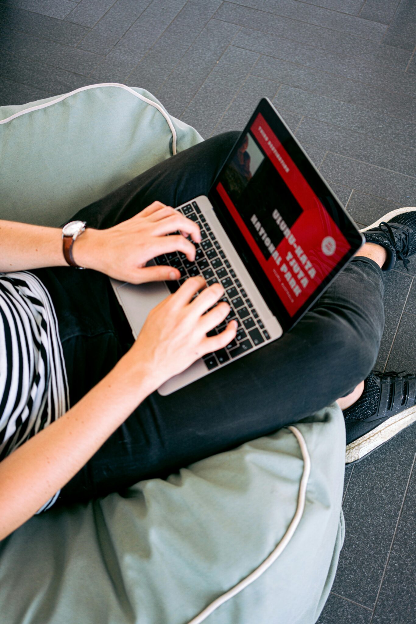 création de site e-commerce. Person working remotely on a laptop while sitting comfortably on a beanbag chair indoors.