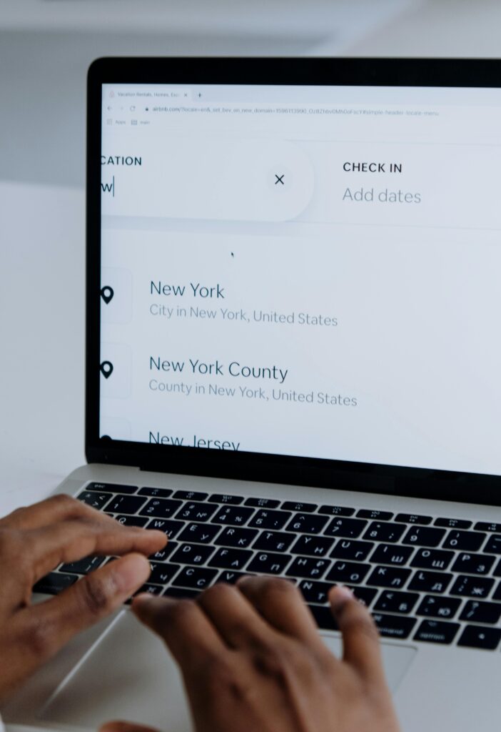création site e-commerce Toulouse. Hands typing on a laptop near New York location search screen.